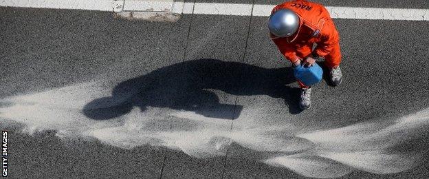 A track marshal covers the oil left by Kevin Magnussen's McLaren