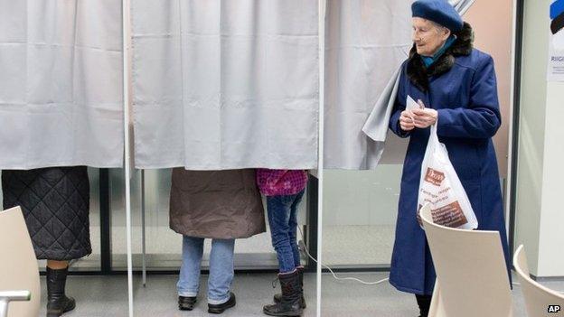 A woman leaves a voting booth at a polling station in Tallinn, Estonia, on Sunday, March 1, 2015