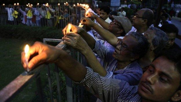 Indian people put candles onto a fence as they protest against the killing of Avijit Roy, a prominent Bangladeshi-American blogger, in Kolkata, India, Sunday, March 1, 2015