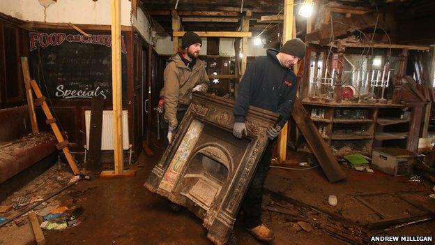 A man carries the fireplace through the main bar area