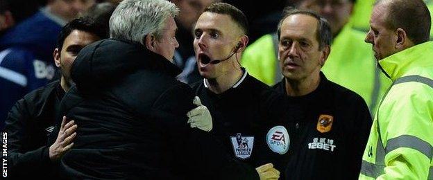 The assistant referee tries to calm Bruce down