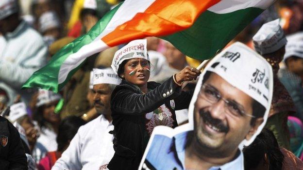 A supporter of Aam Aadmi Party next to a cut-out of party leader Arvind Kejriwal February 14