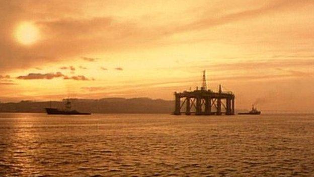 An oil rig and boat at sunset