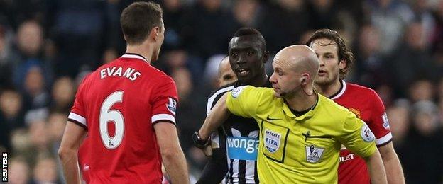 Referee Anthony Taylor holds Jonny Evans and Papiss Cisse apart