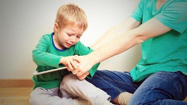 Child with parent trying to take away a tablet device