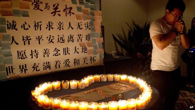 A man, one of the relatives of Chinese passengers onboard Malaysia Airlines Flight 370, prays near candles before a briefing with Malaysian officials at a hotel in Beijing, China, on 31 March 2014