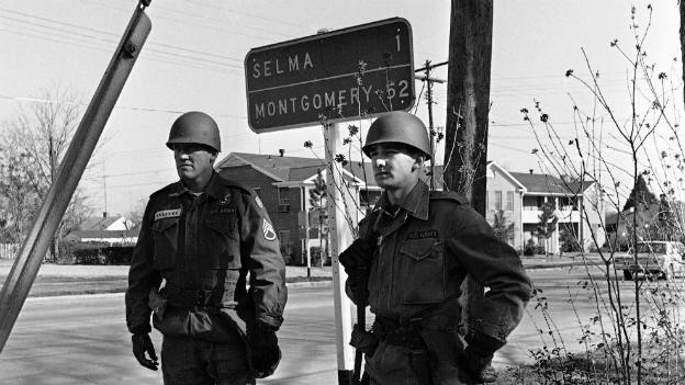 National Guardsmen stand under a road sign showing the distance to the capital - 20 March 1965