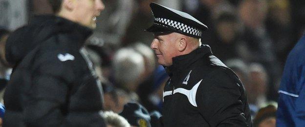 Peter Houston tries on a policeman's hat for size after the wind blew it onto the pitch.