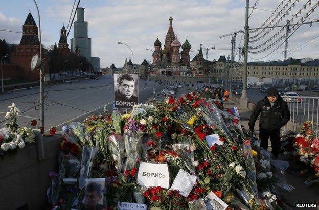 A man passes flowers laid at the spot where Boris Nemtsov was shot, 6 March