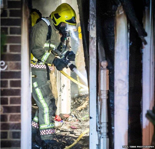 Firefighter extinguishing flames on staircase of Winston Churchill Drive property