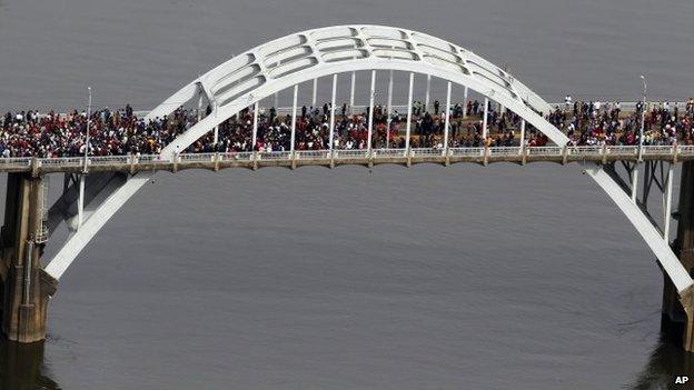 Crowds of people move in a symbolic walk across the Edmund Pettus Bridge, Sunday, March 8, 2015, in Selma,