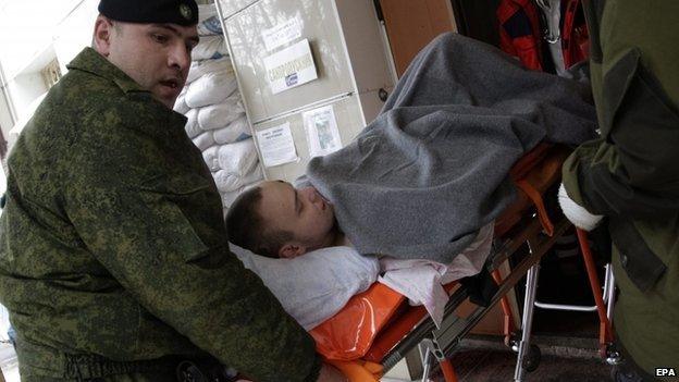 Separatist rebels carry an injured comrade from hospital to an ambulance as they prepare to send injured separatists to Russian town Rostov from Donetsk