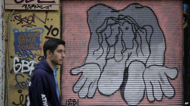 A man walks past a shop with its shutter painted with a mural, in central Athens on Monday, 9 March 2015