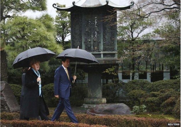 Germany's Chancellor Angela Merkel and Japan's Prime Minister Shinzo Abe (R) walk in the garden as they visit the Nezu Museum in Tokyo 9 March 2015.