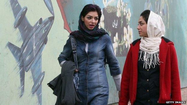 File photo: Two women walk past a mural in the Iranian capital Tehran