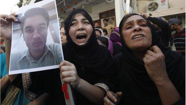 A relative of a supporter of MQM who was detained by paramilitary forces during a raid protests with others along a street in Karachi March 11