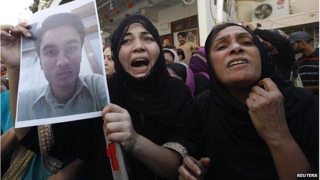 A relative of a supporter of MQM who was detained by paramilitary forces during a raid protests with others along a street in Karachi March 11