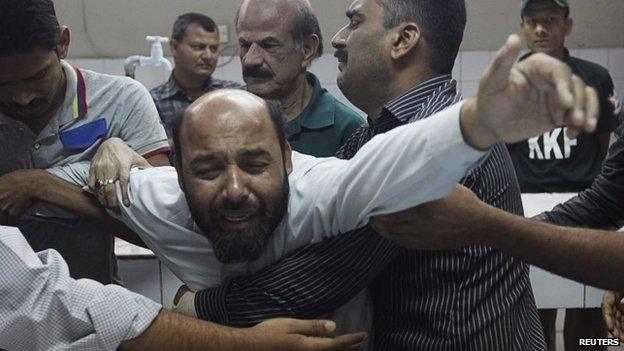 A relative mourning the death of Waqas Ali Shah, a supporter of the Muttahida Qaumi Movement (MQM) political party who was killed during a raid by paramilitary forces on MQM's headquarters, is comforted by others at a hospital morgue in Karachi, 11 March