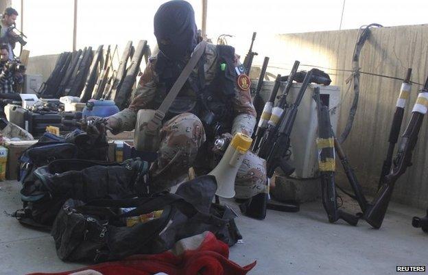 A paramilitary soldier displays weapons recovered during a raid on the MQM party headquarters in Karachi March 11