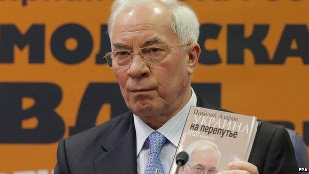 Former Ukrainian Prime Minister Mykola Azarov hold a copy of his book during a press conference to presents his book 4 February 2015