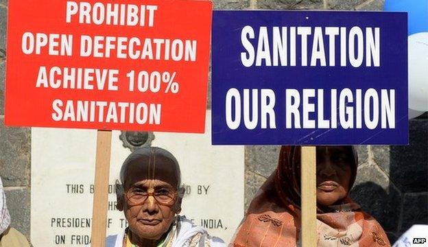 Women holding signs calling for an end to open defecation