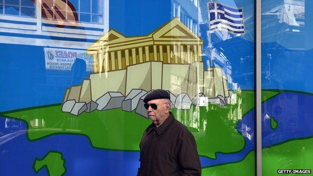 A man walks past a shop window in Athens, with a display of the Acropolis