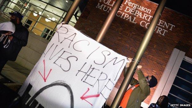 A sign reading "Racism lives here" outside Ferguson police department