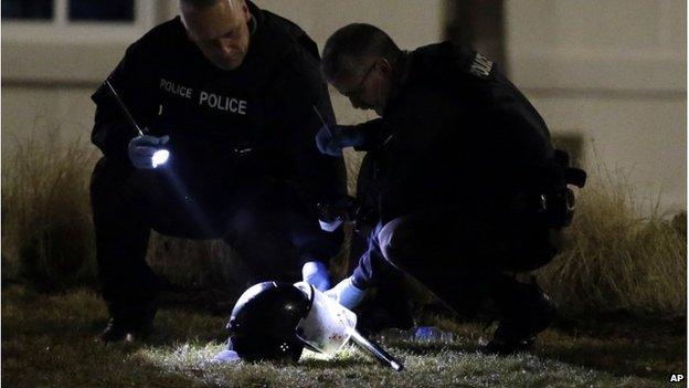 Police examine helmet lying on ground after two officers were shot in Ferguson, Missouri, 12 March 2015