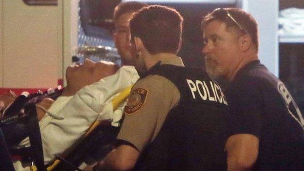 Paramedics carry on a stretcher one of the two injured police officers in Ferguson