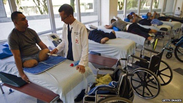 Colombian soldier William Loaiza (left ,attends his rehabilitation therapy session at the Heroes de Paramillo hospital in Medellin on 11 September, 2013.