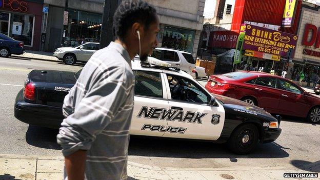 Man walking in front of Newark police car