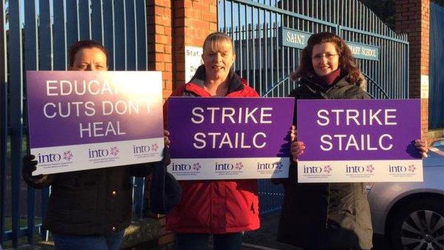 Around two dozen people have gathered with signs, flags and whistles at St Patrick's Primary School in Pennyburn, Londonderry