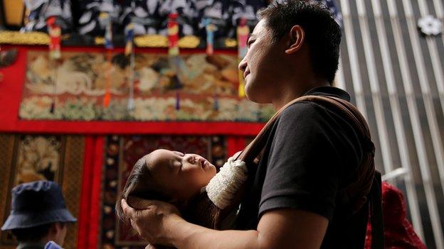 A Japanese father holding his sleeping baby