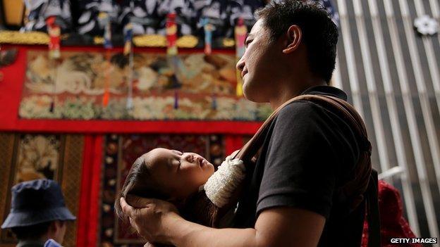 A Japanese father holding his sleeping baby