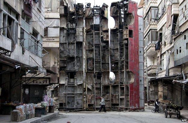 A young boy walks past a makeshift barricade of upturned buses in rebel-held Aleppo - 15 March 2015
