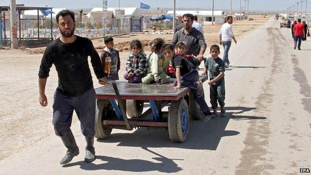 A Syrian refugee pulls a cart carrying children at the Zattari refugee camp near Mafraq city, Jordan - 14 March 2015