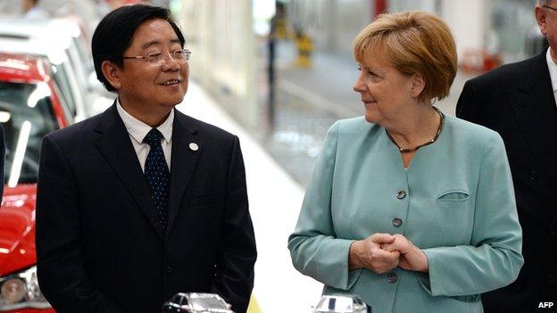 German Chancellor Angela Merkel (R) stands with FAW Group CEO Xu Jianyi