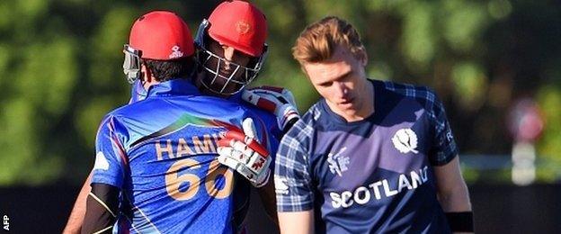 Afghanistan batsmen Hamid Hassan (L) and Shapoor Zadran (C) celebrate as Scotland"s Richie Berrington (R) reacts