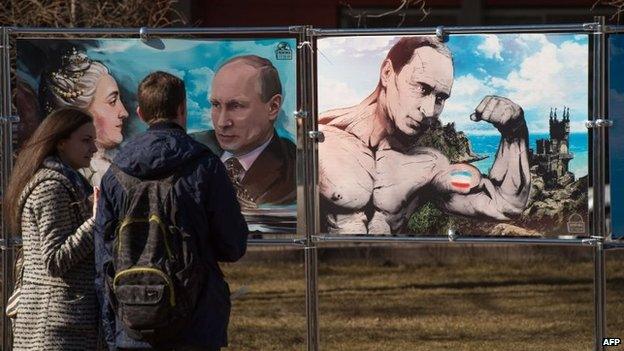 A couple stand next to paintings depicting Vladimir Putin in Crimea (16 March 2015)