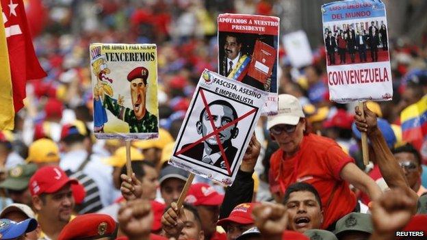 Supporters of President Nicolas Maduro hold up placards depicting during a rally against imperialism in Caracas on 15 March, 2015