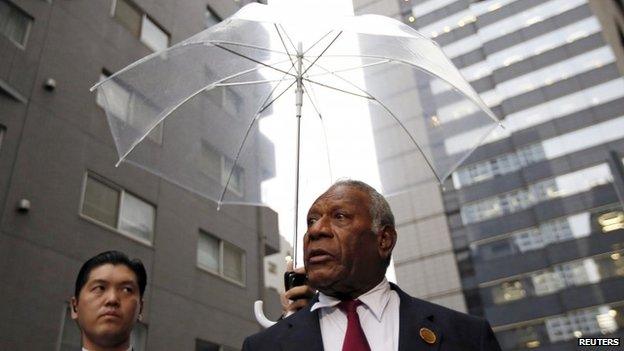 Vanuatu"s President Baldwin Lonsdale (R), flanked by a Japanese security police officer holding an umbrella, speaks in Tokyo - March 16, 2015