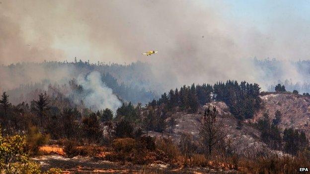 An aircraft flies over the area during fire fighting efforts at Rodelillos, Chile, 14 March 2015.