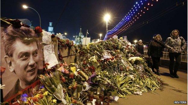 People walk past flowers at the site where Russian politician Boris Nemtsov was killed