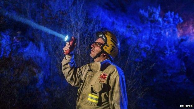 A firefighter use a lamp near a forest fire in the hills of the port city of Valparaiso on 14 March, 2015.