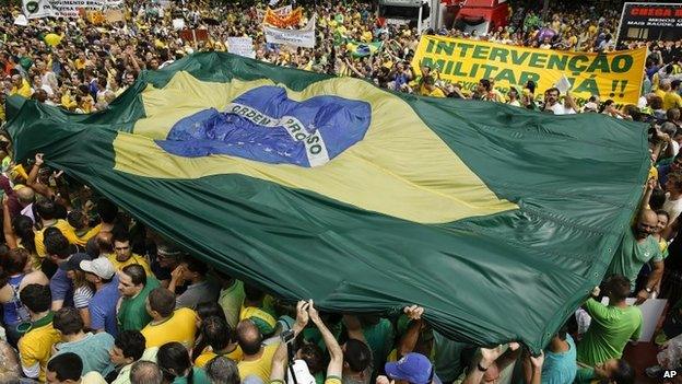 Protesters hold a Brazilian flag aloft