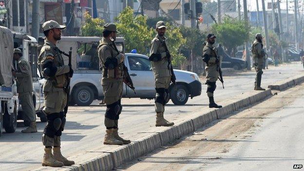 Police stand guard as Pakistani Christians bury the victims of twin suicide attacks in Lahore