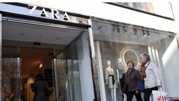 Women hold an H^M shopping bag outside a Zara store