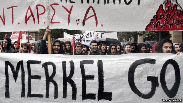 Protesters hold a banner as they march during a demonstration against the visit of Germany's Chancellor Angela Merkel on April 11, 2014 in Athens, Greece