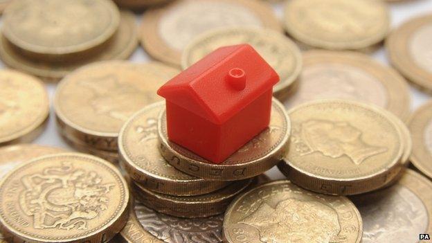 Monopoly house on a pile of pound coins