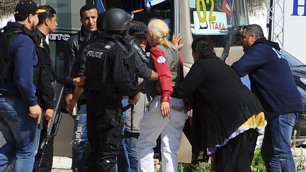 A survivor from the Tunis gun attack being helped onto a bus